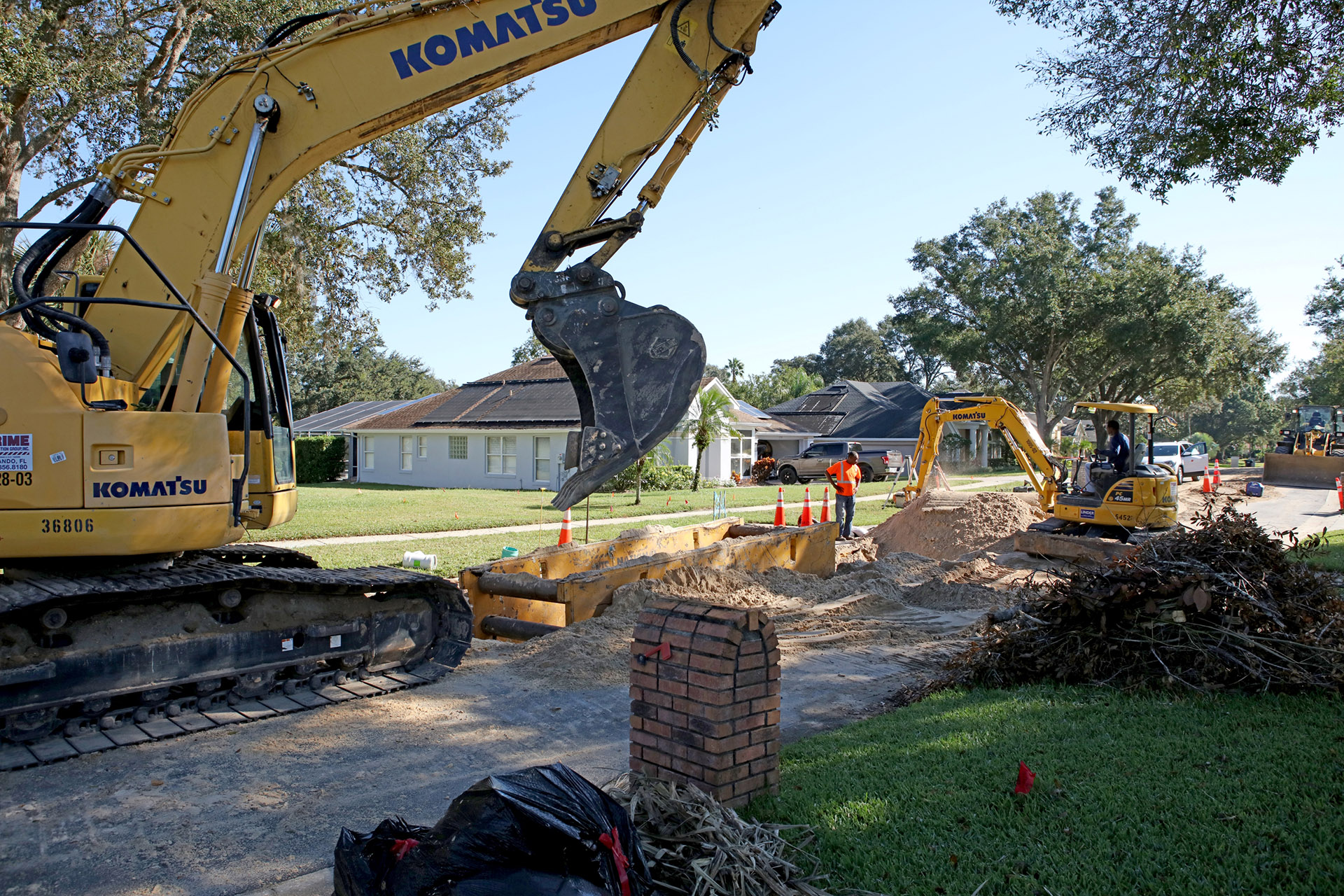 Komatsu excavator digging up road in neighborhood.